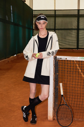a lady wears a beige zip-up hoodie with a black mini dress and sneakers